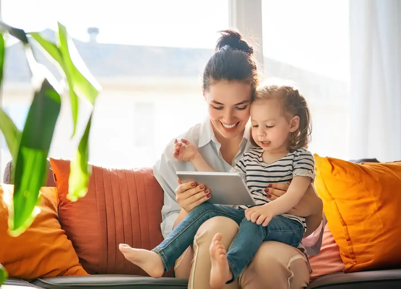 Woman reading to child on couch with orange pillows