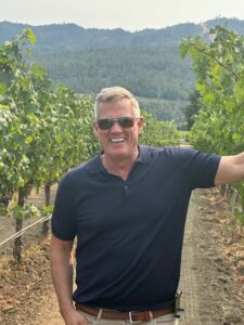 Tom Yancey, owner of Yancey Home Improvements smiling in a vineyard.