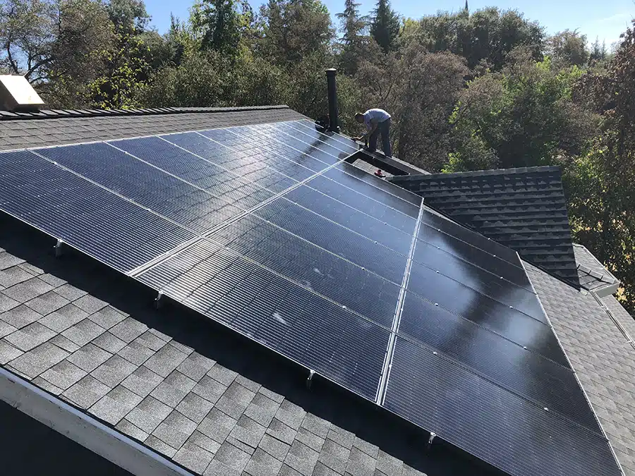 Technician installing solar panels on residential roof in Sacramento, CA.
