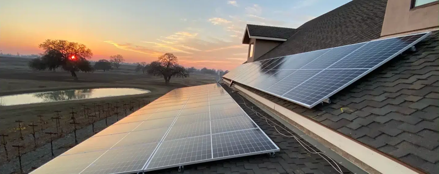 Solar panels on roof with sunset in background in Sacramento, CA.